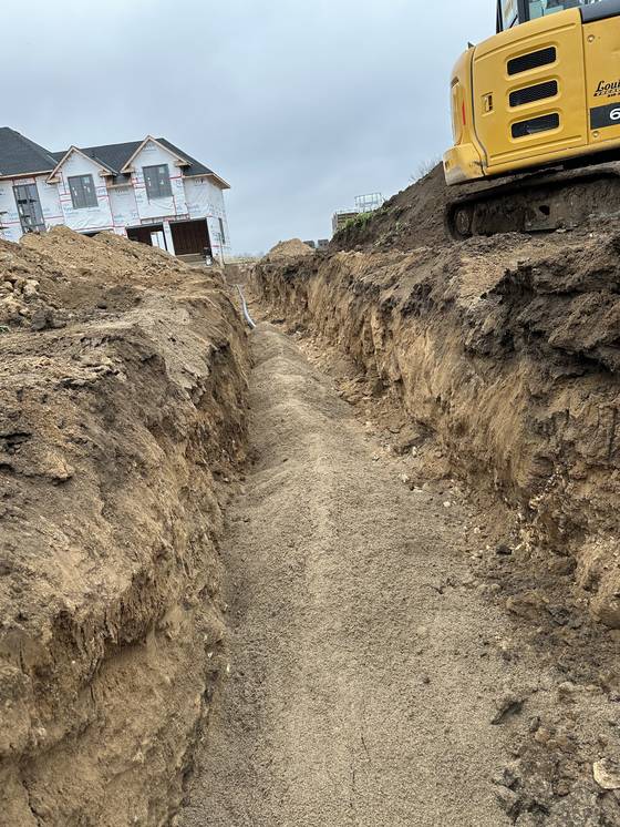 Foundation trench beside a house under construction