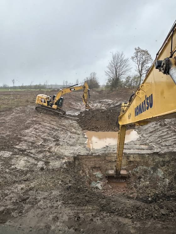 Excavator working in a deep muddy excavation