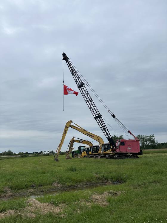 Dragline crane in a field with Canadian flag