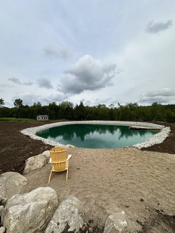 Round pond with rock edge and sandy beach