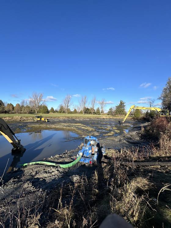 Long-reach excavator dredging a pond